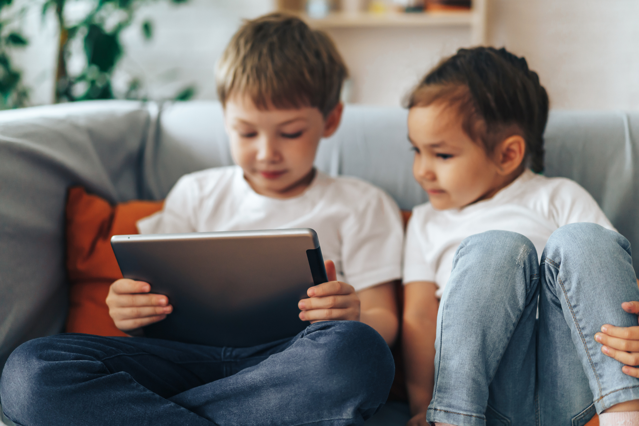 two children on couch with ipad